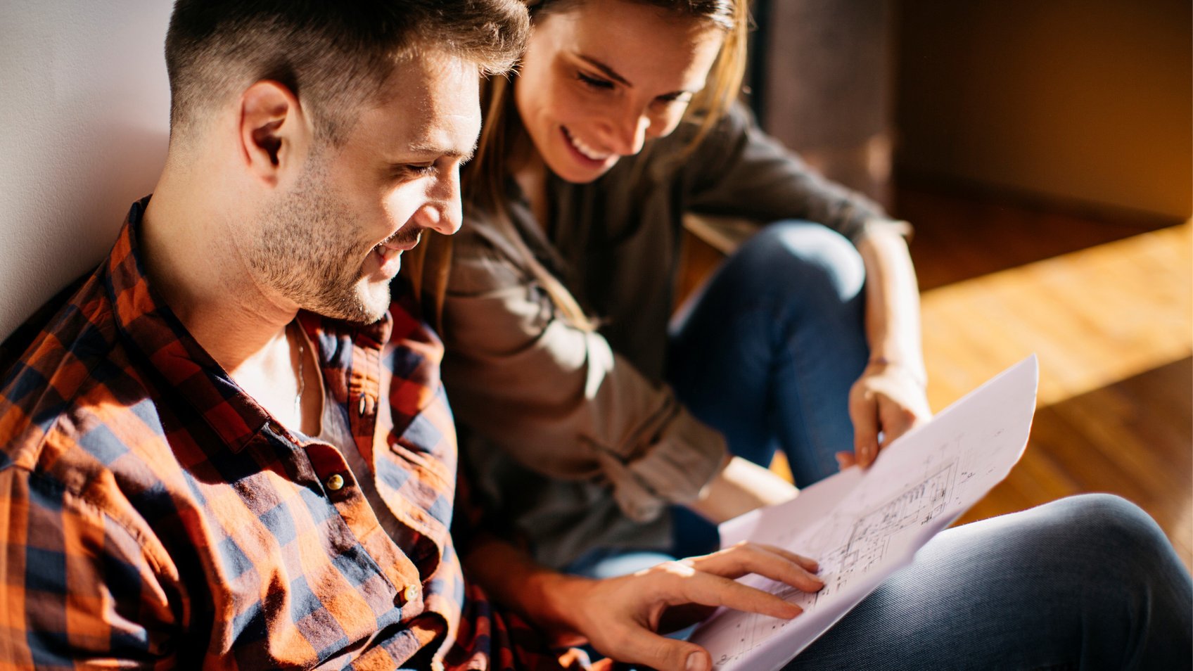 Et par sidder på gulvet og kigger på plantegning 