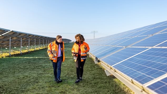 Mand og kvinde går gennem solcellepark